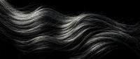 Flowing dark hair strands with silver highlights creating elegant waves against black background for beauty and fashion concepts.