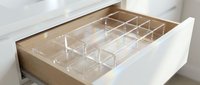 Clear acrylic drawer organizer with multiple compartments in wooden kitchen drawer for utensil storage and home organization solutions.