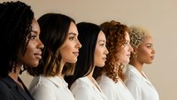Diverse group of five professional women in white shirts standing in profile showing different ethnicities and hairstyles representing workplace diversity.