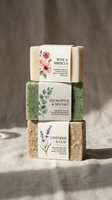 Stack of three handmade soaps with botanical labels featuring rose hibiscus, eucalyptus sea salt, and lavender clay varieties for natural skincare and bath products.