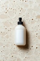 White spray bottle with black pump top on speckled beige textured background, ideal for cosmetics, skincare, cleaning products, or beauty packaging mockups.