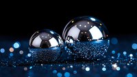 Metallic spheres with blue glitter scattered on dark surface, creating magical atmosphere with bokeh lights and reflective elements. Luxury party decoration.