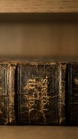 Antique leather-bound books with worn spines and gold lettering arranged on wooden shelf. Vintage library collection showcasing aged literature and classic binding.