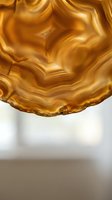 Golden agate slice with natural banded patterns and translucent layers creating organic flowing textures for luxury interior design and geological displays.