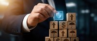 Businessman hand selecting checkmark icon from wooden blocks with business symbols representing success and achievement in corporate strategy.