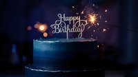 Blue ombre birthday cake with sparkling sparkler and Happy Birthday topper glowing in dark, elegant celebration dessert for party.