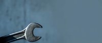 Metal wrench tool on blue background with copy space for mechanical repair and maintenance work projects.