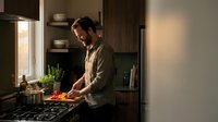 Young Caucasian man cooking fresh vegetables in modern kitchen with natural lighting preparing healthy meal at home for lifestyle and nutrition concepts.
