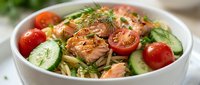 Fresh salmon salad with cherry tomatoes, cucumber slices and dill herbs in white bowl. Healthy Mediterranean diet meal with grilled fish and vegetables.