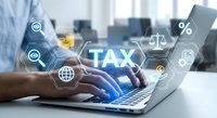 Businessman typing on laptop with glowing TAX icons, finance symbols, and digital hexagonal interface for tax planning and accounting.