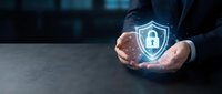 Businessman hands protecting glowing cybersecurity shield with padlock icon representing data protection and digital security solutions for corporate networks.