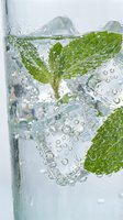 Fresh mint leaves floating in sparkling water with bubbles creating refreshing summer drink for healthy lifestyle and hydration concepts.