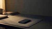 Smartphone on minimalist desk workspace with notebook, coffee mug, and warm lighting for business, productivity, and technology concepts.