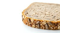 Multigrain bread slice with seeds and nuts on white background isolated for healthy eating and bakery design projects.