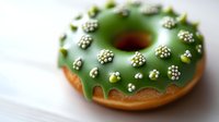 Green glazed donut decorated with white sprinkle clusters on light background, fresh baked pastry with festive holiday topping for bakery and dessert menu.