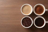 Four white cups with coffee varieties including latte, espresso, black coffee, and roasted beans on a wooden table, top view.