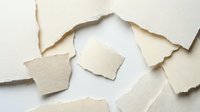 Torn paper pieces scattered on white background creating abstract composition with rough edges and natural texture for creative projects.