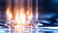 Liquid surface with elegant water columns rising against glowing warm light background, creating dramatic contrast and reflections in macro photography.