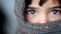 Close up portrait showing expressive brown eyes of young Asian woman partially covered with gray knitted scarf, creating mysterious and artistic composition.