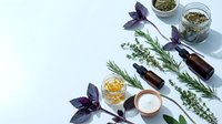 Natural herbs and essential oils spa wellness arrangement with rosemary thyme basil and aromatherapy bottles on white background for holistic health.