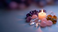 Healing crystals and gemstones arranged around glowing candle for meditation, spiritual wellness, chakra balancing and holistic therapy practices.