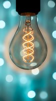 Vintage Edison bulb with spiral filament glowing against turquoise bokeh background for creative lighting and energy concepts.