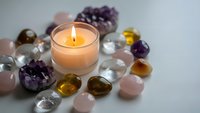 Healing crystals and gemstones surrounding glowing candle for meditation, spiritual wellness, chakra balancing and holistic therapy practices.