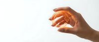 Hand holding glowing golden orb of light against white background, symbolizing energy, innovation, and success for business and technology concepts.