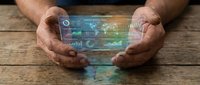 Senior businessman hands protecting holographic data analytics dashboard with charts and graphs on wooden desk for technology and business concepts.