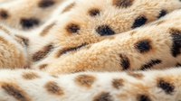 Close up macro shot of cheetah fur texture showing distinctive black spots on beige background, natural animal print pattern for wildlife and nature design projects.