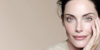 Young Caucasian woman with natural makeup touching face showing healthy glowing skin for skincare beauty routine and cosmetic treatment concept.