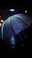 Blue umbrella with raindrops illuminated by street lights against dark night background, creating magical atmosphere with bokeh effects and falling rain.