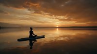 Silhouette of person sitting on wooden dock at tranquil lake during golden sunset with dramatic clouds reflected in calm water creating peaceful meditation scene.