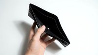 Empty black leather wallet held in hand showing no money financial crisis bankruptcy concept isolated on white background.