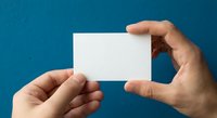 Hands holding blank white business card mockup against blue background for branding and corporate identity design projects.