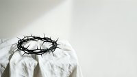 Crown of thorns resting on white fabric with dramatic lighting, symbolizing sacrifice and redemption for religious and spiritual content.