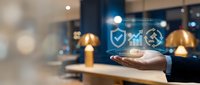 Business professional displaying digital security analytics icons with shield chart and gear symbols floating above open palm in modern office environment.