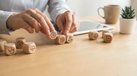 Professional woman arranging wooden blocks with business icons on desk for strategic planning and organization in modern office workspace.