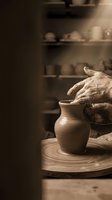 Potter's hands shaping clay vessel on spinning wheel in studio workshop. Artisan crafting ceramic pot with traditional pottery techniques and tools.