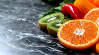 Fresh kiwi and orange slices arranged on dark marble surface, ideal for food, nutrition, and healthy lifestyle content.