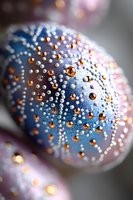 Decorative Easter egg adorned with intricate pattern of white and copper rhinestones on blue surface, creating elegant holiday decoration with sparkly festive detail.