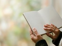 Open book held by hands with blurred natural background, suitable for education, reading, learning, and literary content projects.