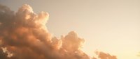 Dramatic golden clouds illuminated by warm sunlight creating ethereal atmosphere during sunset or sunrise with soft glowing light and peaceful sky.
