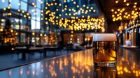 Golden beer glass on polished bar counter with warm bokeh lights creating cozy pub atmosphere for hospitality and nightlife concepts.