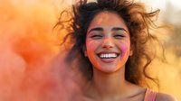 Young Hispanic woman with curly hair and bright smile against orange sunset background, wearing natural makeup and pink blush, expressing joy and happiness.