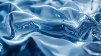 Flowing blue silk fabric with elegant waves and soft folds creating luxurious textile background for fashion and design projects.