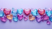 Colorful glass heart shapes in pink, blue and purple arranged in decorative border pattern on purple background, suitable for romantic designs and holiday cards.