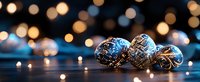 Vintage silver and blue Christmas ornaments with delicate patterns against dark background with soft golden bokeh lights creating festive holiday atmosphere.