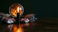 Vintage Edison bulb glowing warmly beside dried lavender bundles and amethyst crystals on wooden surface creating cozy atmospheric lighting for home decor.