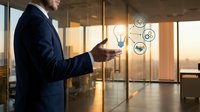 Professional businessman in dark suit holding smartphone with glowing lightbulb and gear icons representing innovation and technology in modern office.